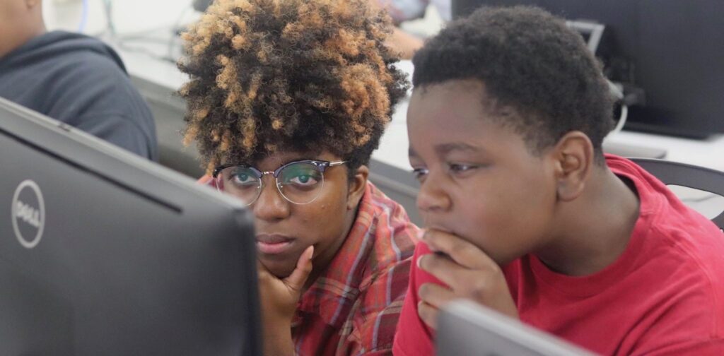 A young child and a young women looking thoughtfully at a computer screen.