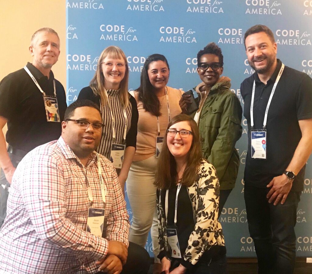 Group of people posing with a background that says Code for America.