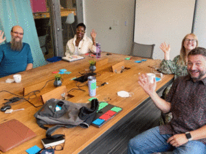 Gif of Software for Good leadership team sitting around a table with sticky notes and waving at the camera.